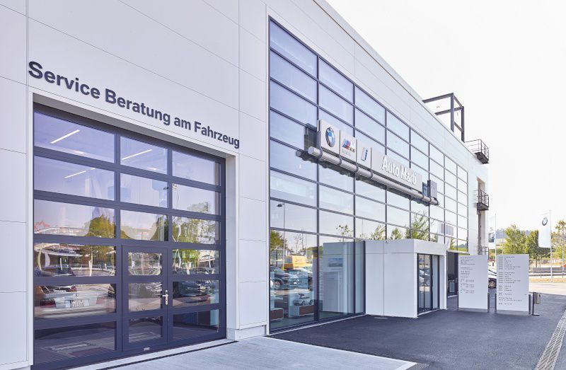 Außenansicht des modernen Autohauses Auto Marti mit Glasfassade, Sektionaltor und Schriftzug Service Beratung am Fahrzeug.