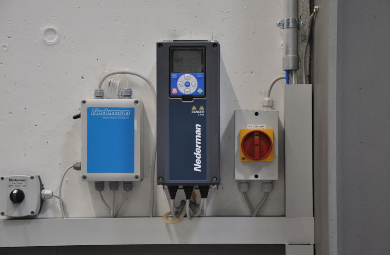 Bedieneinheit und Steuerung einer Absauganlage von Nederman an der Wand montiert, mit Schalteinheit und elektrischen Anschlüssen.