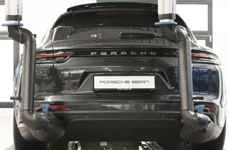 Rückansicht eines Porsche-Fahrzeugs auf einer Hebebühne in der Werkstatt der Filiale in Bern, mit beidseitig positionierten Absaugarmen.