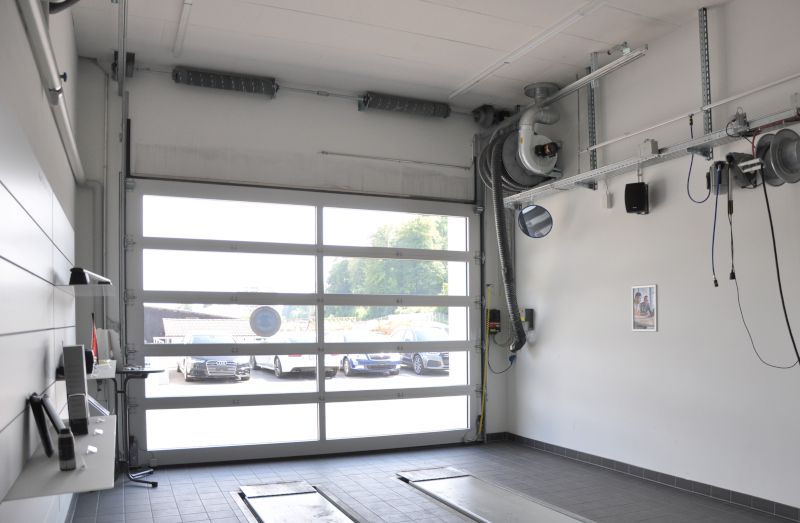 Atelier lumineux avec porte sectionnelle; ventilateur d'aspiration mural Nederman avec tuyau à droite