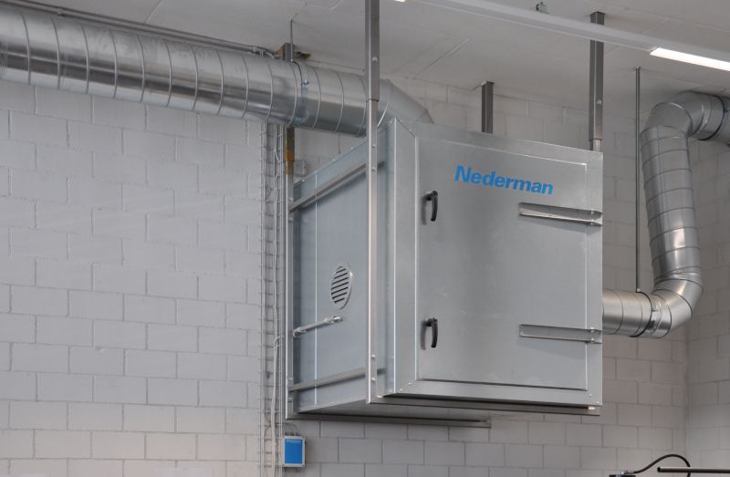 Système de filtration et de ventilation Nederman argenté au plafond, relié à des tuyaux métalliques dans un local industriel